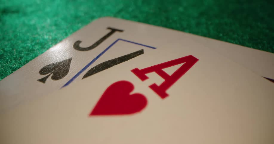 Ace of hearts is placed on jack of spades on green felt surface