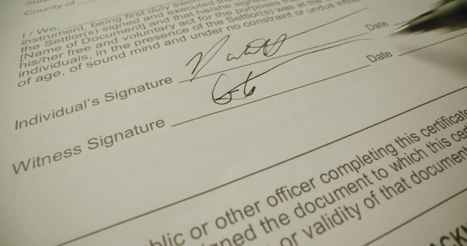 A pen as it signs a piece of paper in the witness signature spot