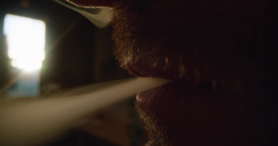 Smoke streams out of a mans mouth and nose as he exhales while smoking