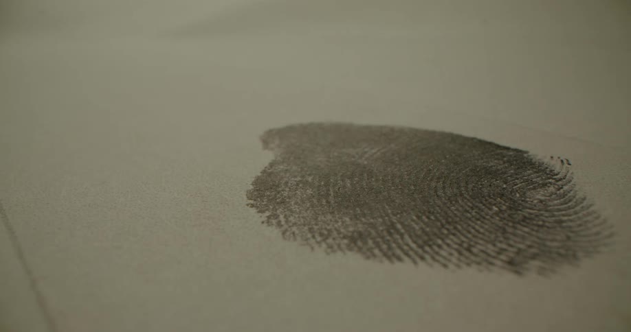 Inked finger presses against paper leaving a fingerprint