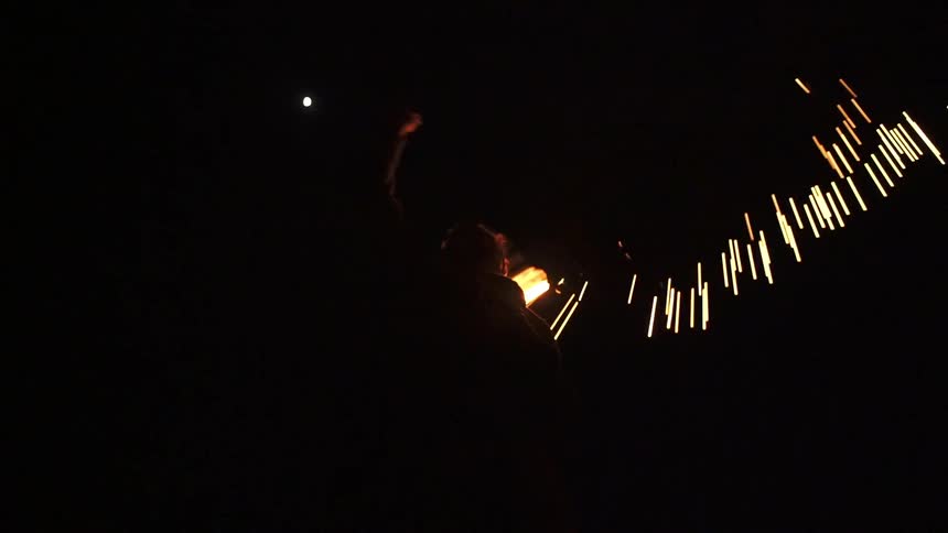 A man is spinning fire in a night sky
