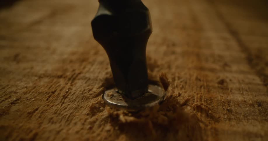 Screw is screwed into a piece of wood with a drill bit