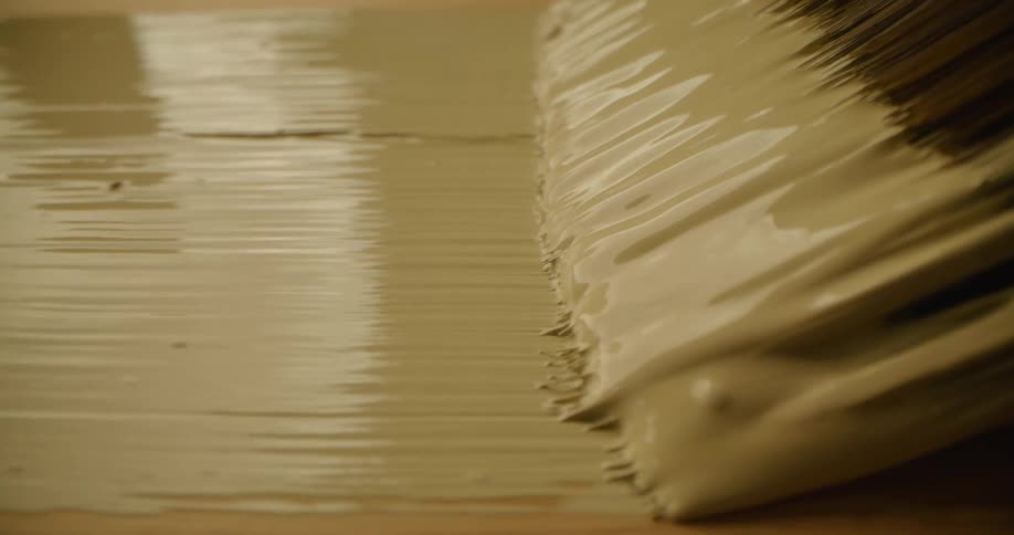 A close up of a person painting a piece of wood