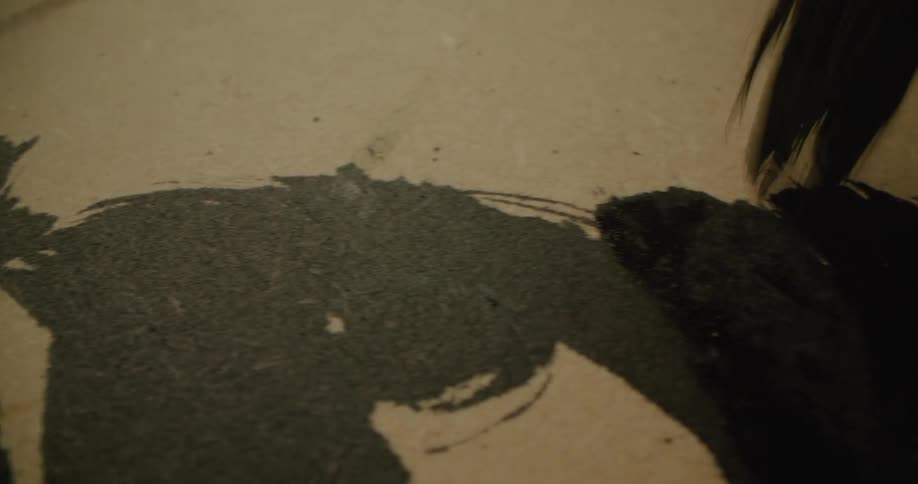 Black paint being applied on a brown surface with a paintbrush