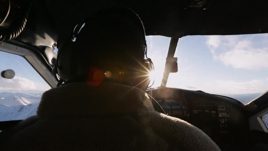 A pilot sits in the cockpit, flying a plane