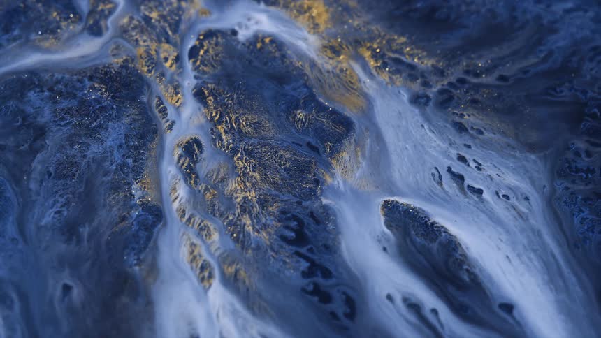 Blue white and gold colors that look like sand and water on a mountain range