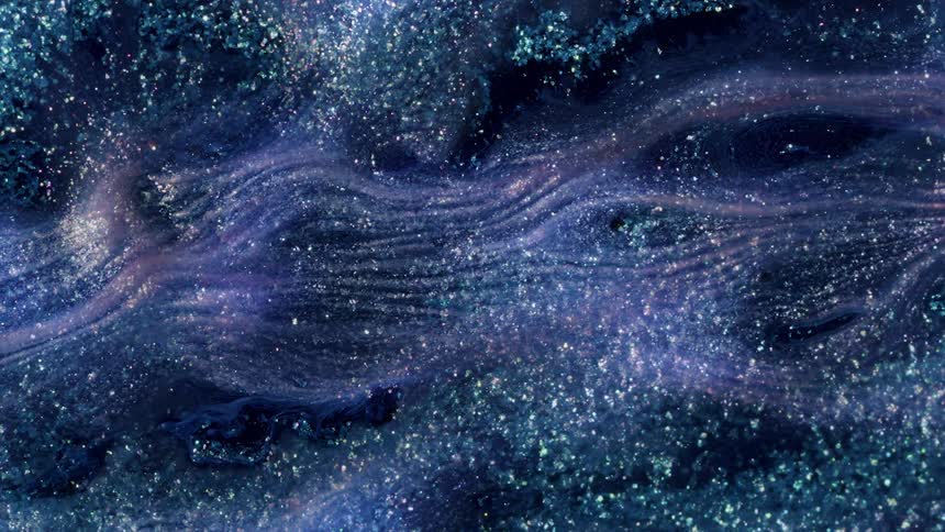 A macro shot of silver glitter shimmers in purple liquid as it flows in curved lines