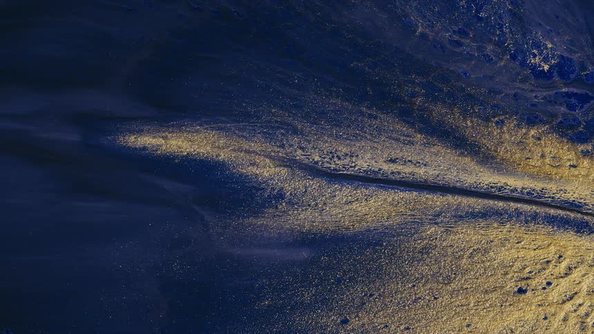 a river of golden paint unfolds on dark blue paint across the scene
