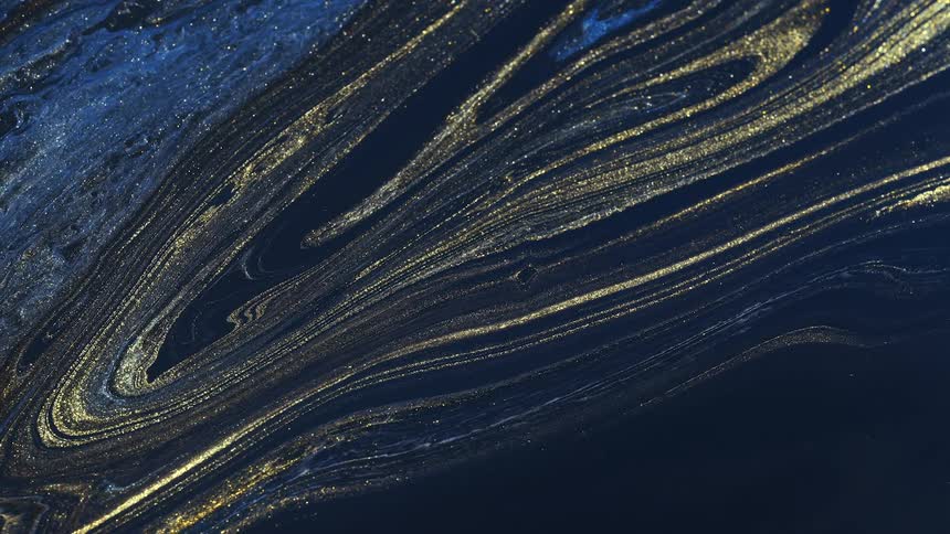 Gold streaks flow through black and blue colored mixture