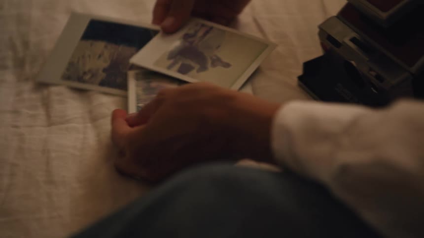 Two women are sitting down looking at polaroid pictures
