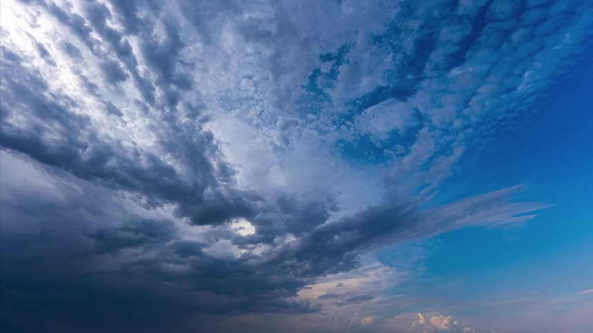 Dark clouds travel through the blue sky during the day