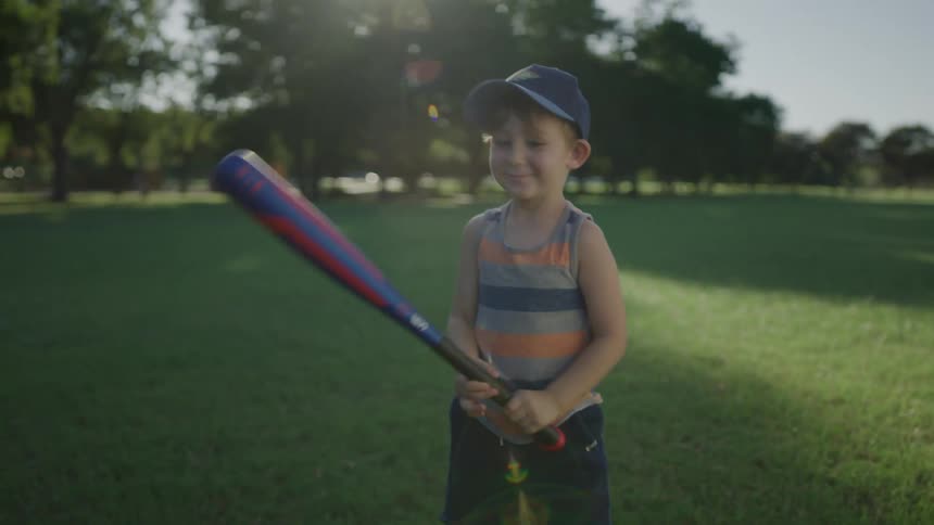 A boy holding a bat jumps up and down as he waits for his dad to throw a baseball