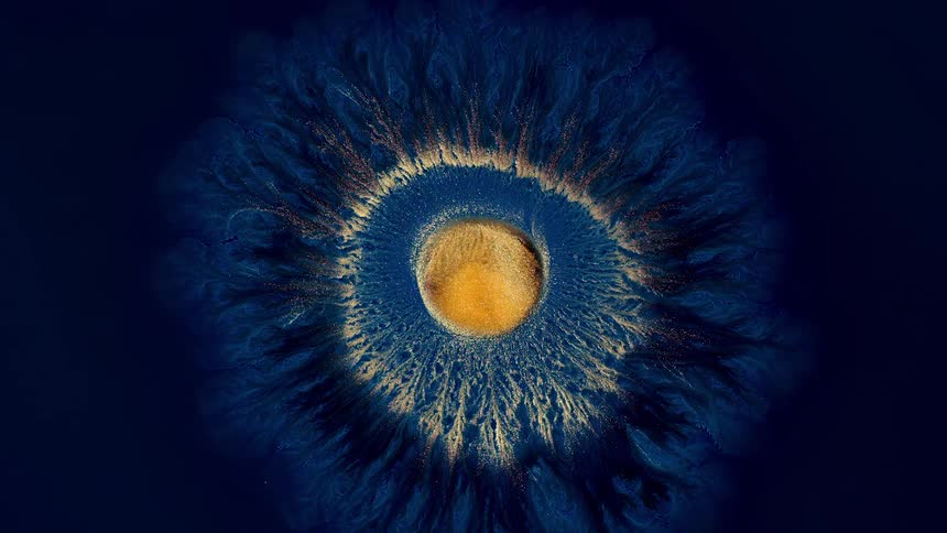 A drop of golden ink expands in a unique pattern like a flower