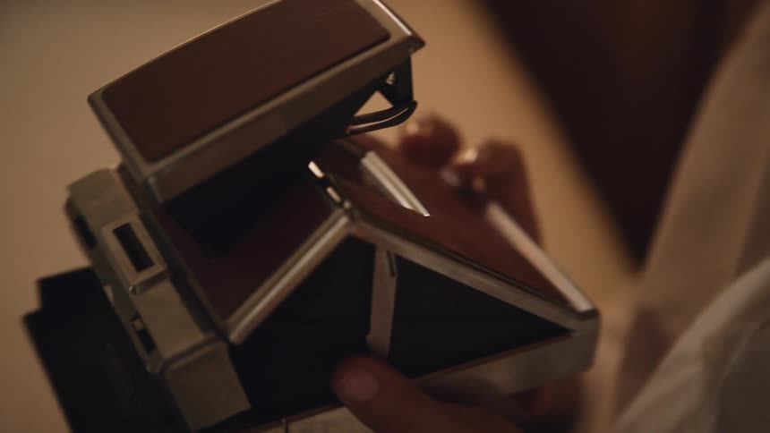 Woman examines old polaroid camera before raising it to her eye