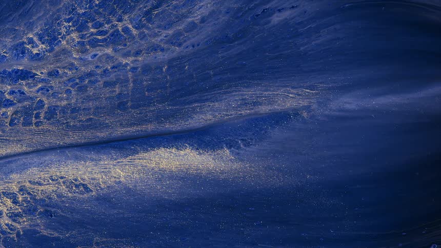 Gold sparkles through spreading blue smoke