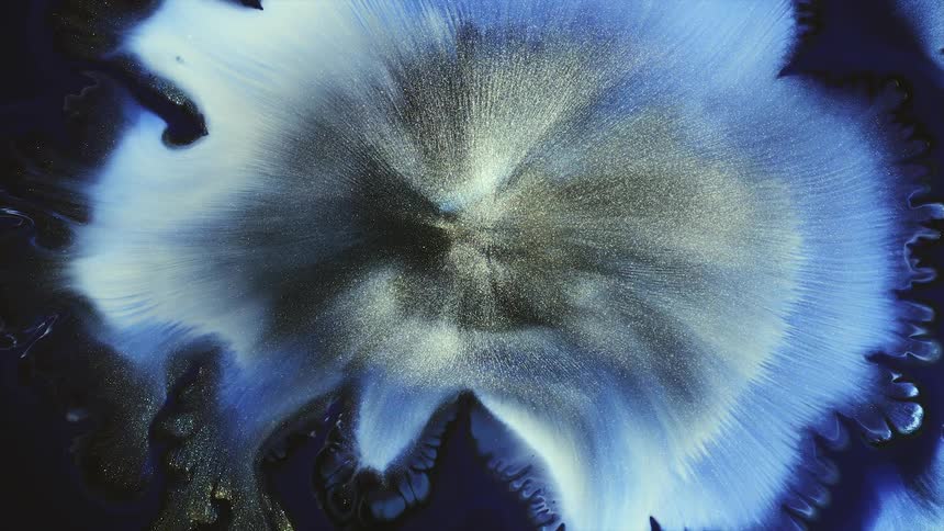 Colorful silver gold tendrils spread out at center of expanding swirling blue surrounding by darker shades