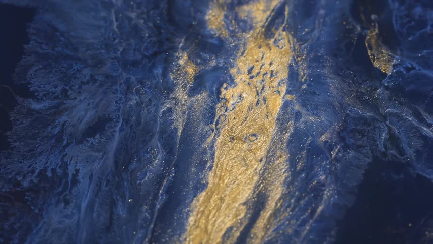 Sparkling golden liquid flows on blue dark background and rotates