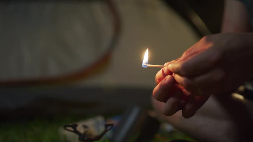 A man lighting a match for a camping stove