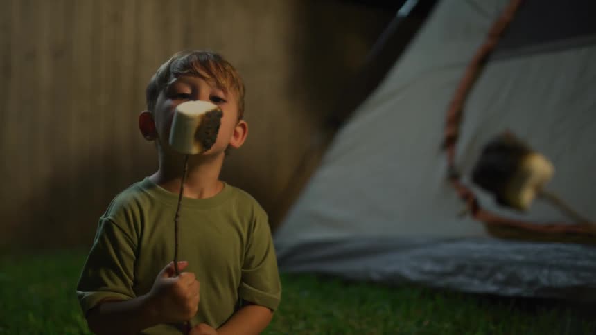 A boy is roasting a marshmallow on a campfire