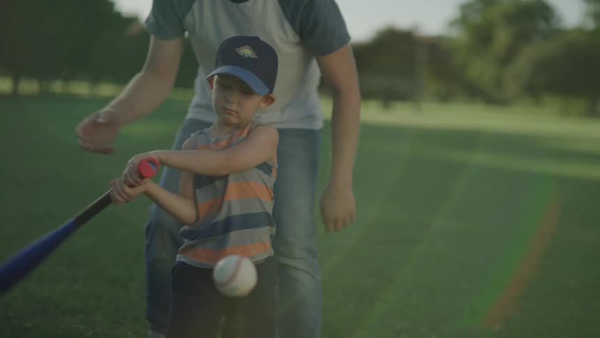 Father teaching his son how to hit a baseball with a bat
