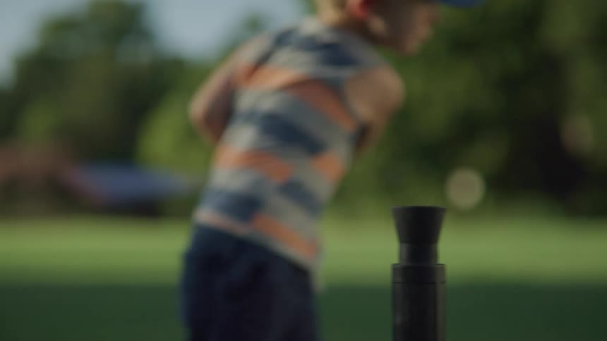 A young boy hitting a baseball outside on a summer day