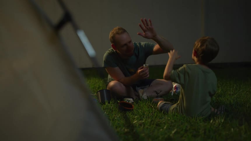 A man and a boy sitting on grass and eating