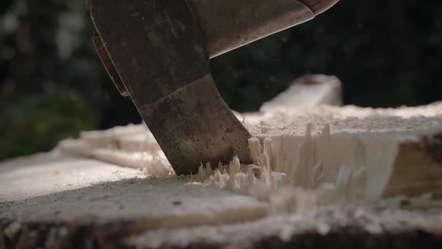 An axe chops into a piece of wood