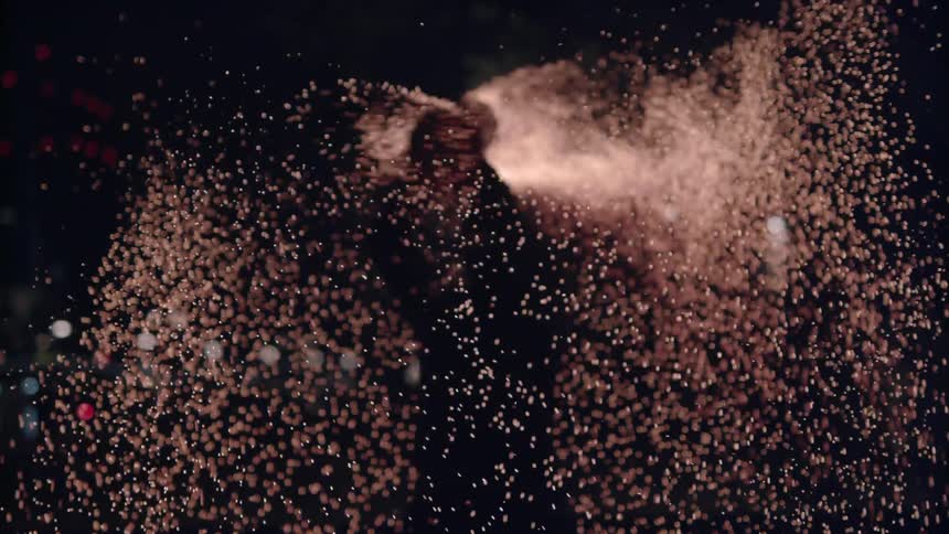 A person twirls a fiery sparking stick at night