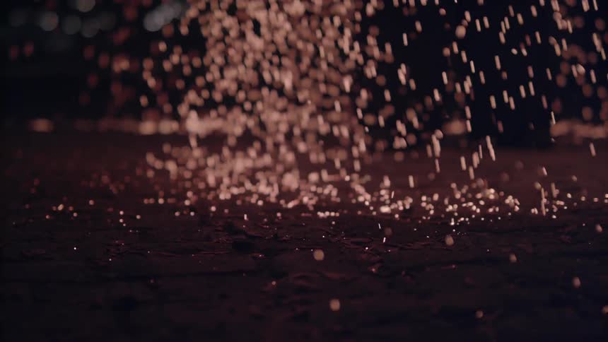 Sparks fall onto a dark ground