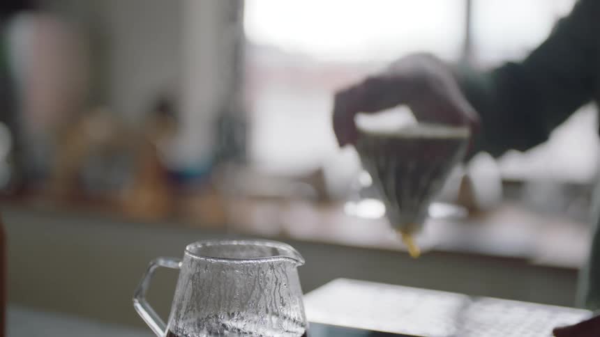 A man removes the cone from a pour over coffee maker