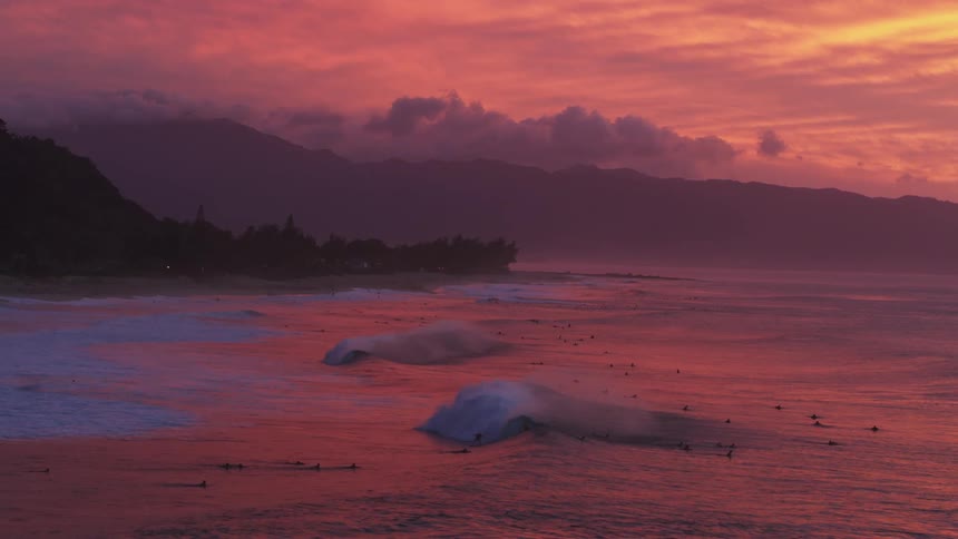 Perfect barrelling waves roll in at sunset on the north shore of Oahu, Hawaii