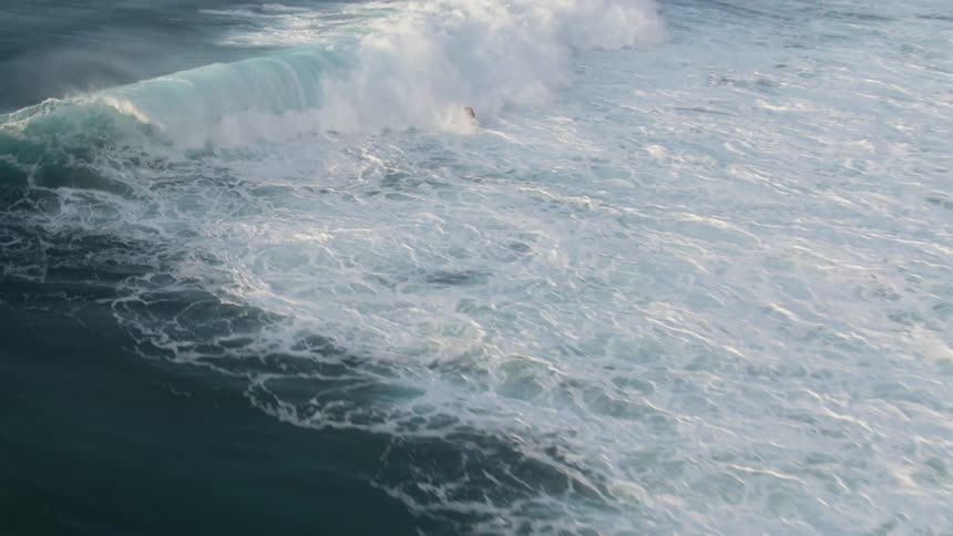 A person surfing on a surfboard on a wave with the sky and clouds in the background