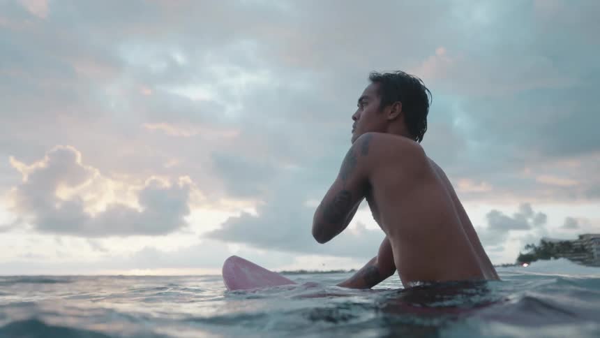 A man sitting on a surfboard in the ocean