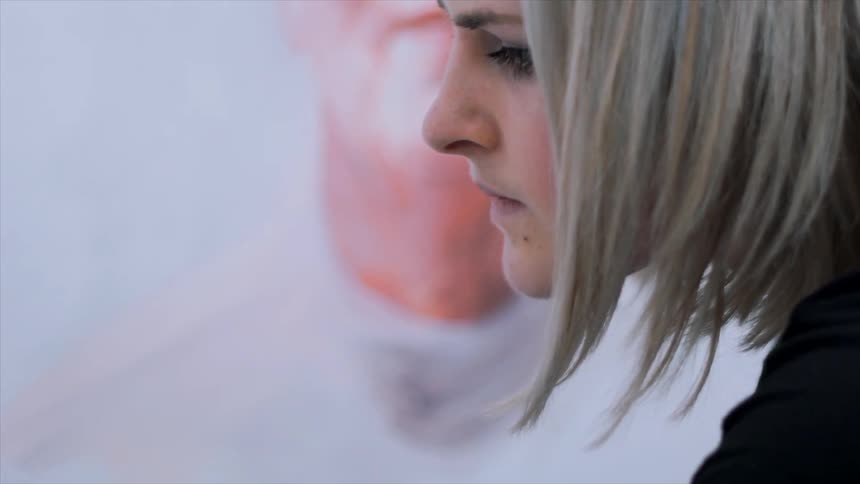 A woman is looking forward in front of a painting