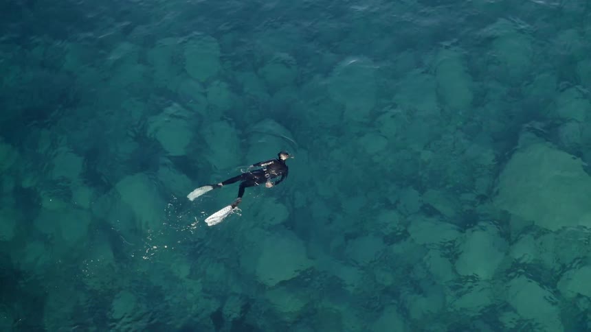A person with a wetsuit and flippers swimming in water