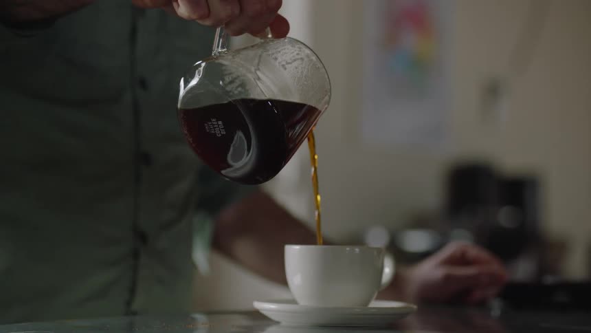 A man pours coffee into a coffee cup
