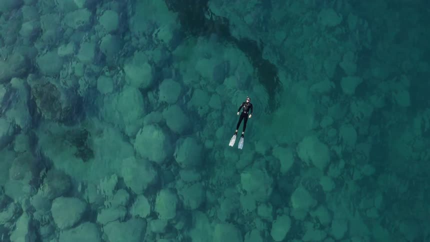 A diver leisurely floats on their back in the ocean during the day