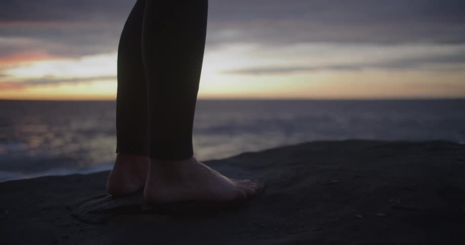 A person standing on a beach with the ocean sky and clouds in the background