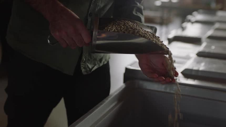 A person uses a large scoop to get animal food out of a bin in a warehouse