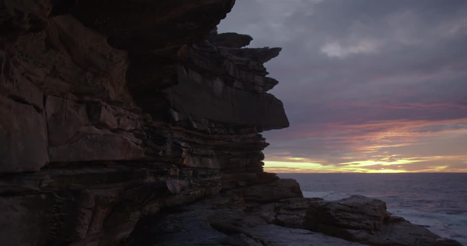 Ocean waves roll into shore near the rocky cliff