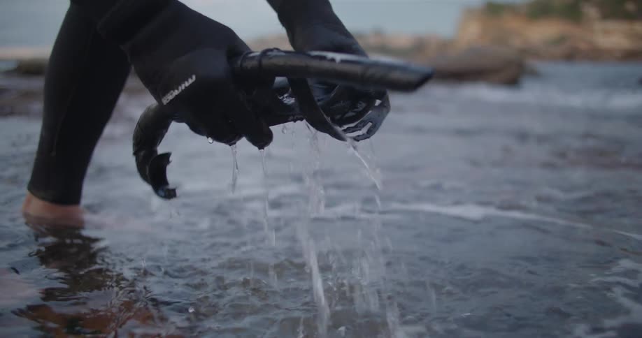 Man cleaning a snorkel and diving goggles with sea water in the coast