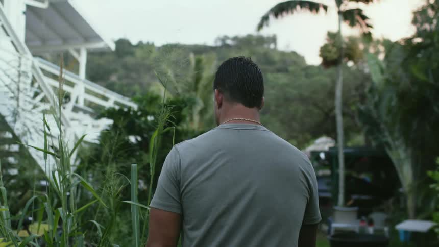 A man walking outdoors near some plants