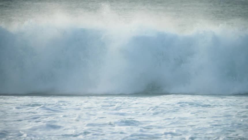 A male surfer riding an ocean wave in the daytime