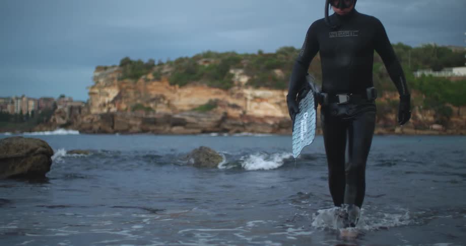 A man in scuba gear walks out of the water
