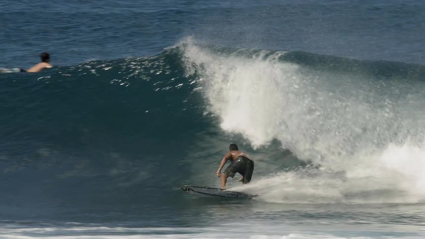 A man riding a surfboard on a wave crashes into the water