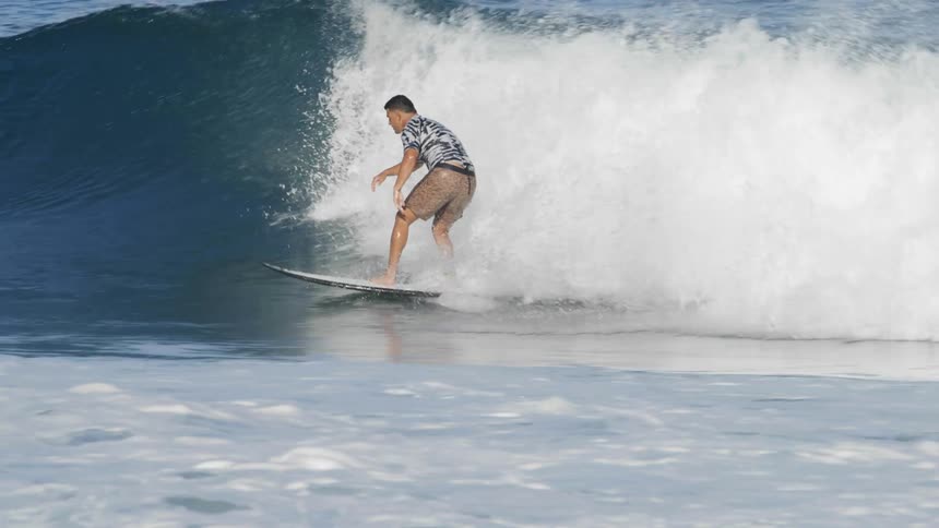 A man is riding his surfboard in the ocean
