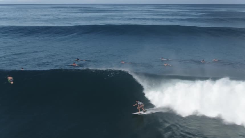 A man is riding a large wave on his surfboard