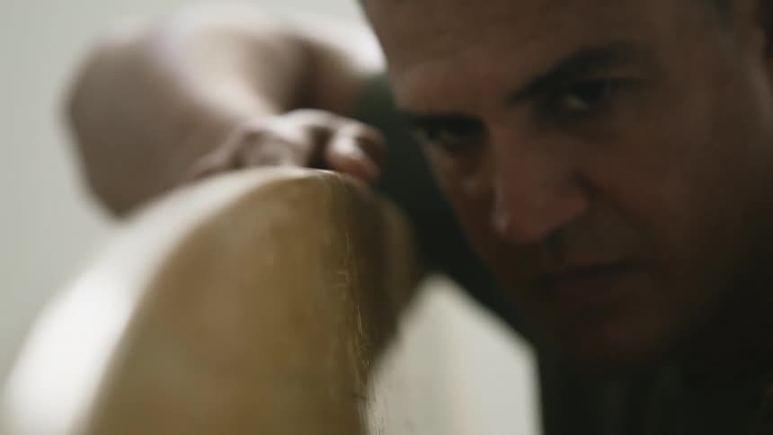 A man runs his hands along a wood service near his face