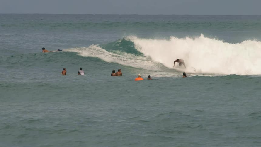 Wide shot of a group of people watching a person surf