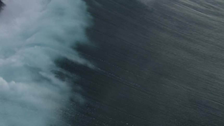 Huge wave splashing as it rolls in and over a surfer